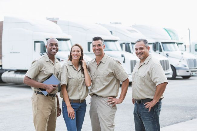 A team of truck drivers stands in front of their fleet of vehicles.