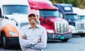 A small business owner stands smiling in front of her fleet of vehicles.