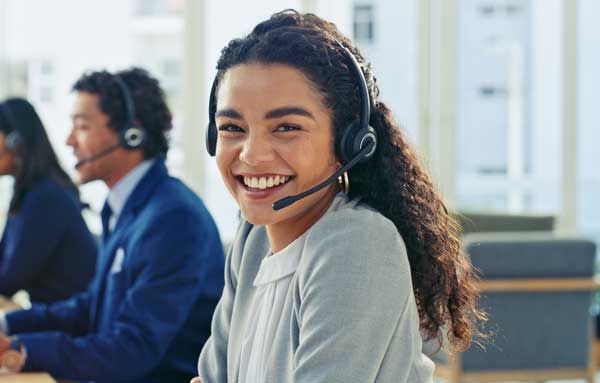 A customer service center representative smiles between calls.